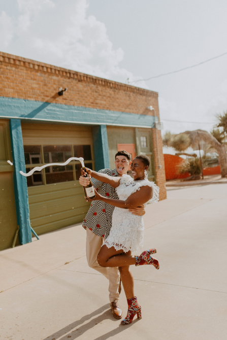 Two people opening a bottle of bubbly outdoors