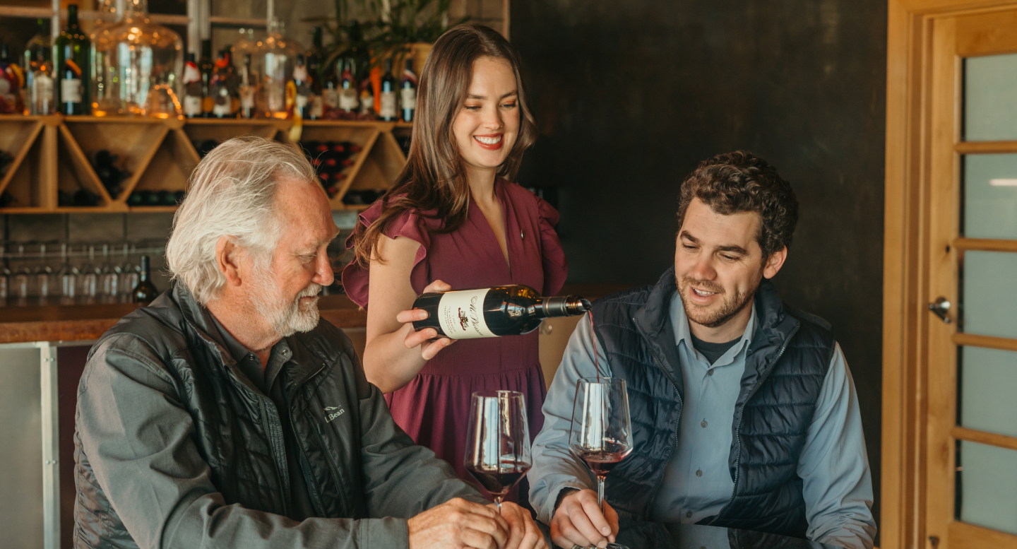 Female server pouring wine for McPherson men